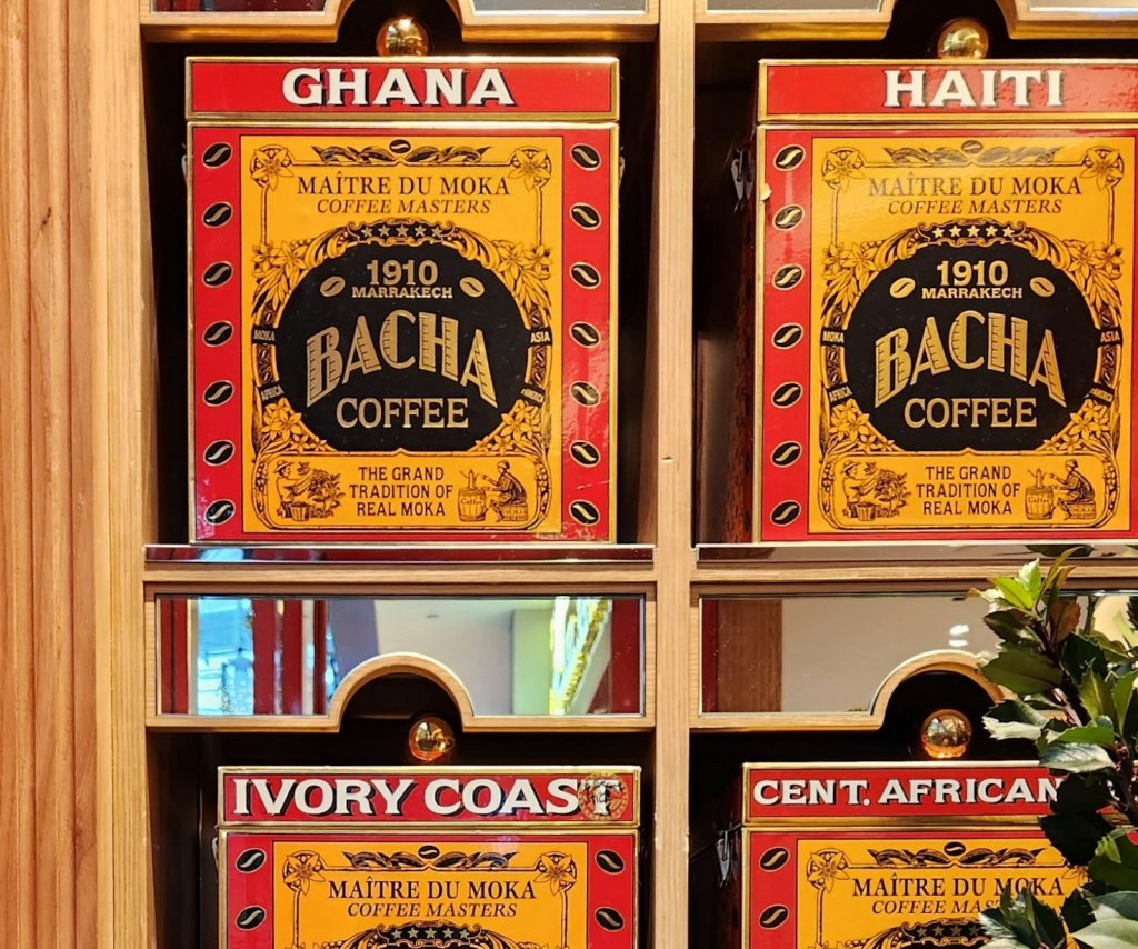 A wall of identical red-and-gold coffee tins, each labeled only with its origin
