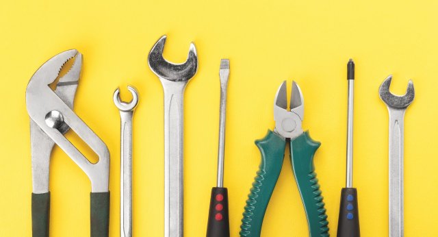 Hand tools arranged on bright yellow background