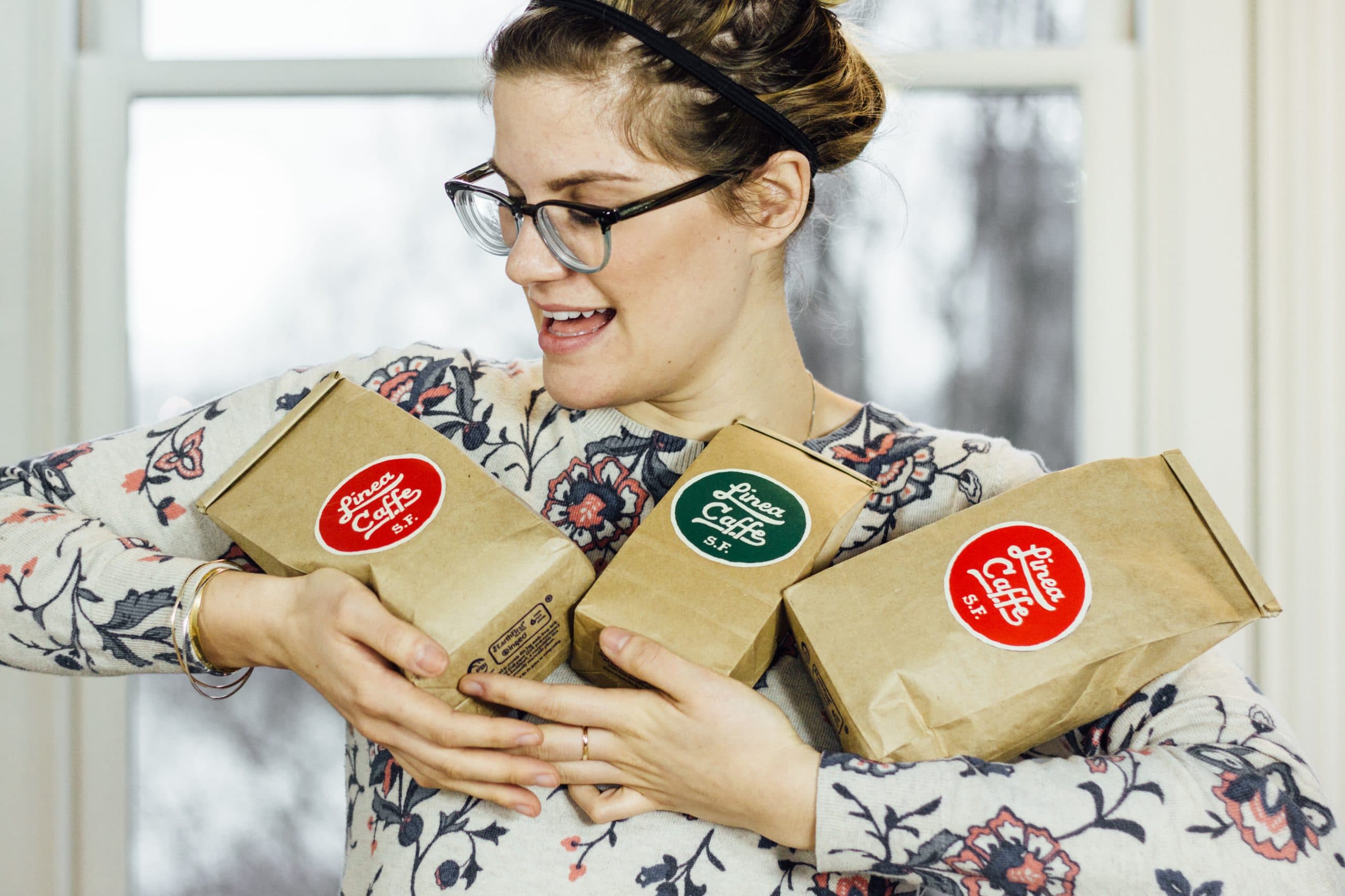 Melissa holding a trio of Linea Caffee coffee bags with much love.