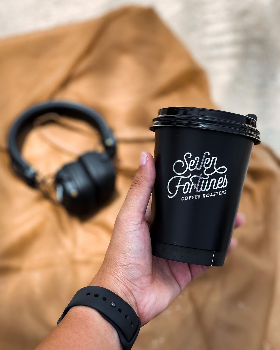 Foil version of Seven Fortunes logo on a black to-go cup